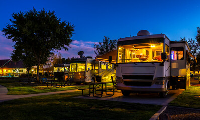Rving at a resort in the evening lighted sky with class A rigs interior lights on