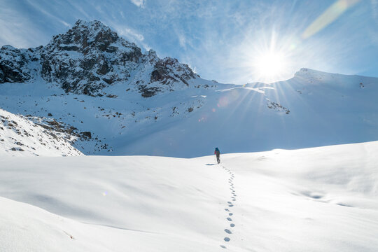 Man walking alone in fresh snow in Alps in winter on a sunny day, Vanoise national park, France