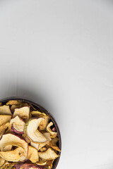 Homemade crispy sun dried organic apple slices. Close up of apple chips with spice in bowl isolated on white background with copy space for text