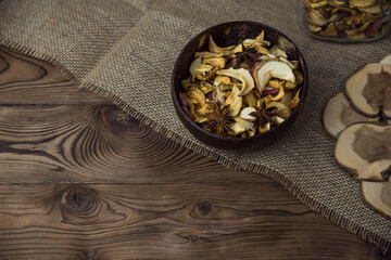 Homemade crispy sun dried organic apple slices. Close up of apple chips with spice in bowl on brown wooden background with copy space for text