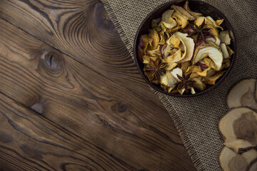 Homemade crispy sun dried organic apple slices. Close up of apple chips with spice in bowl on brown wooden background with copy space for text