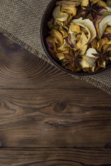 Homemade crispy sun dried organic apple slices. Close up of apple chips with spice in bowl on brown wooden background with copy space for text