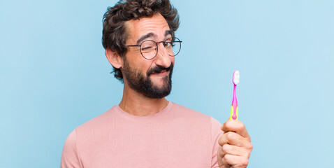 young bearded man looking happy and friendly, smiling and winking an eye at you with a positive...