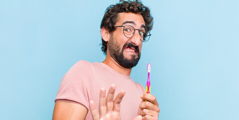 young bearded man feeling disgusted and nauseous, backing away from something nasty, smelly or...