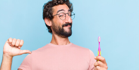 young bearded man feeling proud, arrogant and confident, looking satisfied and successful, pointing...