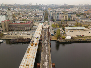 Aerial drone view. Construction of a bridge across the Dnieper river in Kiev. Cloudy autumn morning.