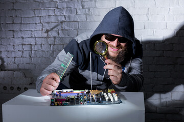 Bearded hacker in sunglasses and hoodie cracking the hardware