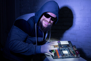 Bearded hacker in sunglasses and hoodie cracking the hardware