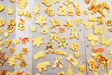 Raw Christmas cookies of different shapes made by children lying on a baking sheet ready for preparation in oven