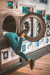 Chica dentro de una lavadora, tratando de sacar la ropa
