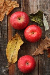 Juicy red apples and autumn leaves on the table
