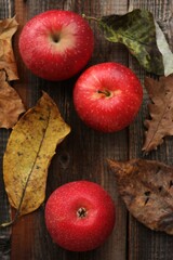 Juicy red apples and autumn leaves on the table
