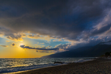 Beautiful shoreline scene with waves at sunset beams