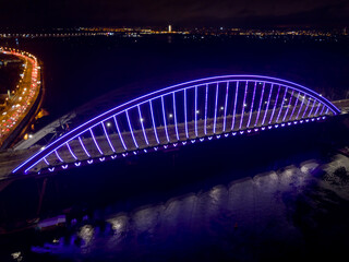 Aerial drone view. Modern arch cable-stayed bridge in Kiev in the evening. Colored lighting of the...