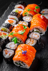 set of sushi roll with salmon, avocado, cream cheese, cucumber, rice, tuna in plate on black background