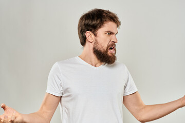 bearded man gesturing with his hands in a white t-shirt aggression light background