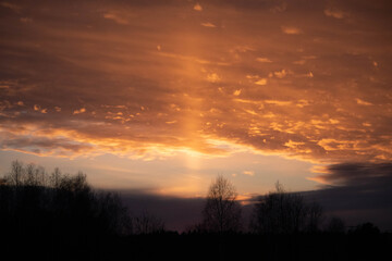 Fototapeta na wymiar Promień zachodzącego słońca na tle kolorowych chmur