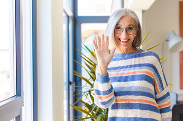 middle age woman smiling happily and cheerfully, waving hand, welcoming and greeting you, or saying goodbye © kues1