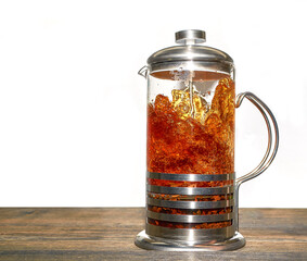 A French press for making coffee and tea, filled with black tea, is on the table.