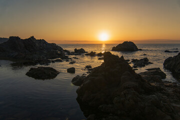 Amanecer desde la playa entre rocas