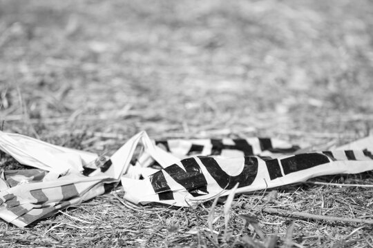 Caution Tape on Grass Ground - Black and White Photo
