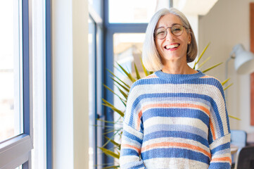 middle age woman looking happy and friendly, smiling and winking an eye at you with a positive...