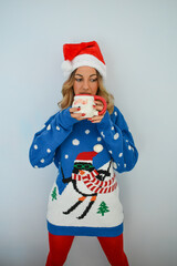 Woman wearing sweater and Christmas hat, having a cup of coffee in hand.