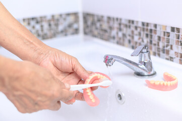 Brush old woman hand to clean denture