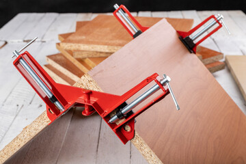 Chipboard in an angular carpentry clamp. Fixing the material for machining.
