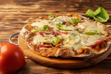 Vegetarian pizza with paprika on a wholegrain flour dough on a wooden Board