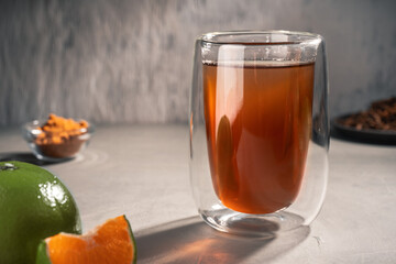 Black tea with green Mandarin oil in a double-walled glass, closeup