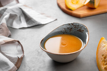 Cream of pumpkin soup in a bowl on a gray table with pumpkin slices on the background