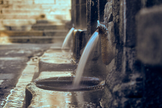stone hot springs pouring boiling water. burgas of orense. blur stone background. water jet with silk effect and steam