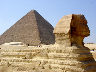 Sphinx and Cheops pyramid against the background of yellow sand and blue sky