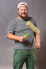 Joyful bearded craftsman with brush roller studio portrait