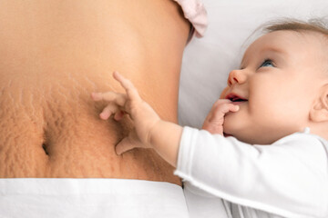 cute baby girl and mom's belly with stretch marks - obrazy, fototapety, plakaty