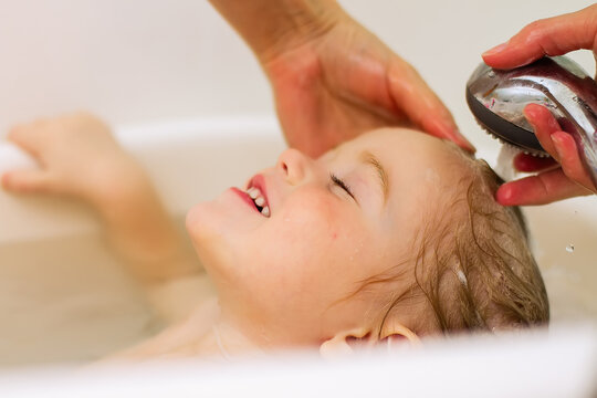 A Little Girl Is Happy And Happy Washing Her Hair In A Baby Bath.