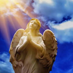 Human soul as angel with wings looking up at the sky in rays of light. Ancient statue.