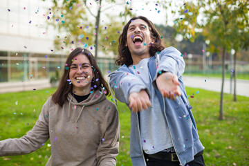 Fototapeta premium two friends having fun celebrating with confetti outdoor