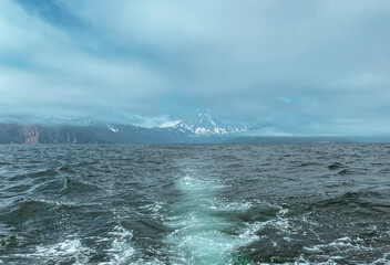 Snow covered volcano view from the stormy sea