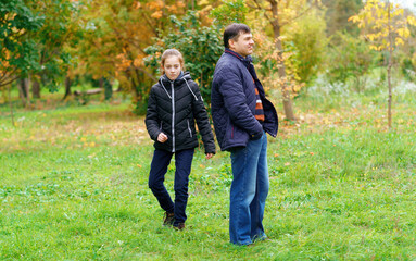 Naklejka na ściany i meble father and daughter walking outdoor in autumn city park, no emotion and unhappy, walk separately, this is the problem of poor communication
