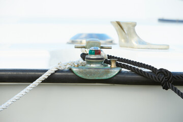 Close up of the bow of a sail boat in a marina, with lines, ropes and navigational lights in focus.