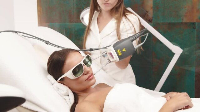 cosmetologist using neodymium laser on female face