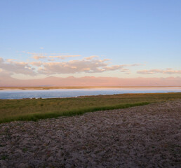 Sunset over salt lake in Atacama desert with orange mountains, Chile