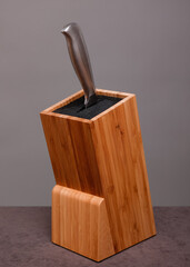 Wooden knife block with knife on grey background 