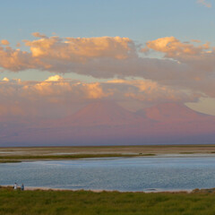 Sunset over salt lake in Atacama desert with orange mountains, Chile