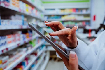 Fotobehang Close up of pharmacist scrolling on digital tablet checking medication walking through isles in pharmacy  © Prins Productions