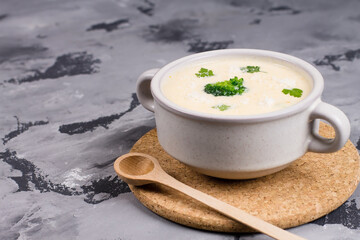 Cheese soup with herbs, in a plate, on a gray background, top view