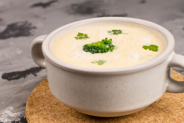 Cheese soup with herbs, in a plate, on a gray background, top view