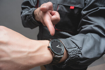 Car service worker is pointing on the wrist watch on his hand close up. Fast service. - obrazy, fototapety, plakaty